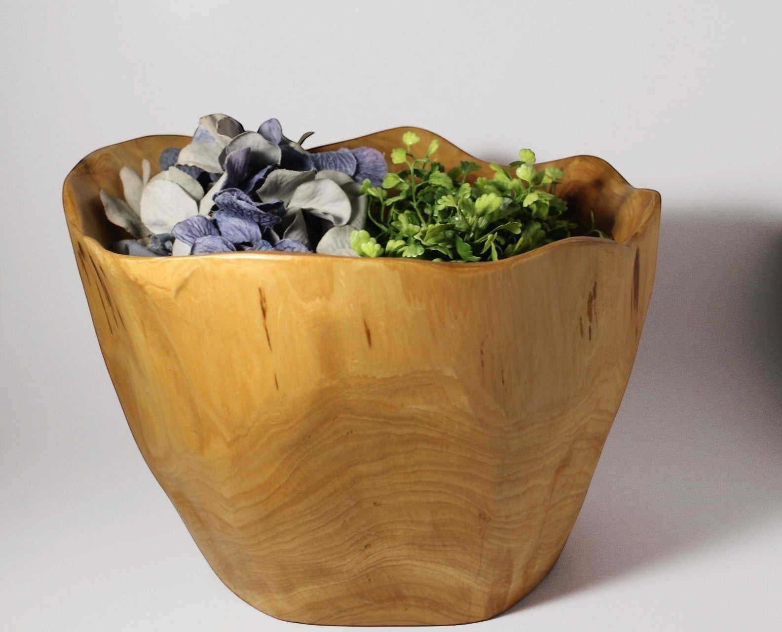 Natural Wonders USA food safe cedar wood bowl, 8" tall, with a unique organic shape and natural grain pattern, filled with faux flowers and greenery.