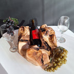 Natural Wonders USA Cedar Single Bottle Wine Holder with a bottle of red wine, grapes, and wine glasses.