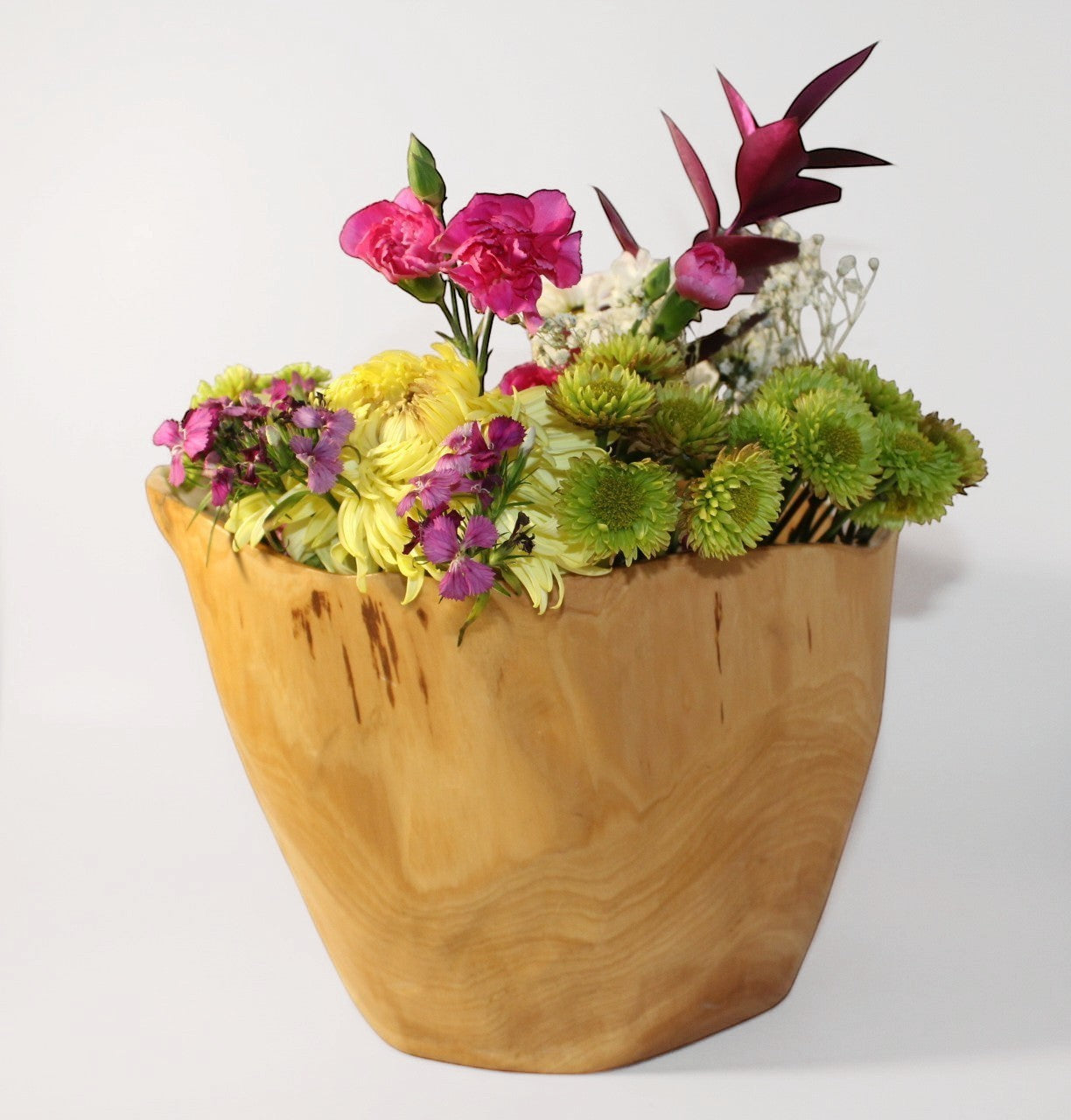 Natural Wonders USA food-safe cedar wood bowl with a unique organic shape, filled with a vibrant floral arrangement.