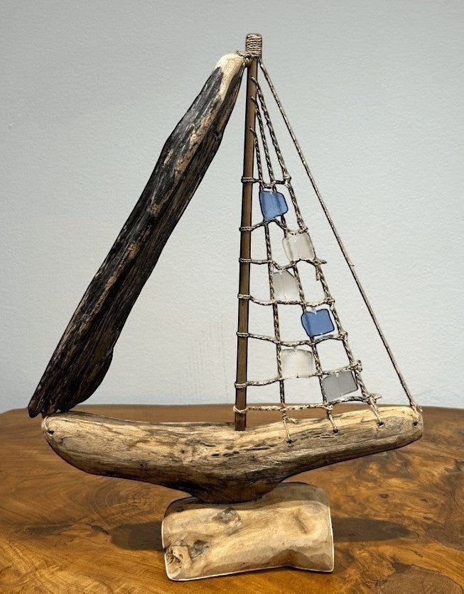 Natural Wonders USA sea glass and driftwood boat sculpture with blue and clear glass sails on a wooden base.