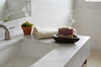 Natural Wonders USA dark wood heart-shaped soap dish holding two bars of soap on a marble countertop.