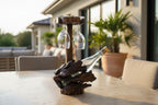 Natural Wonders USA rustic dark wood wine bottle holder with two hanging wine glasses and a wine bottle.