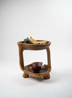 Natural Wonders USA teakwood tier stand, 12" tall, displaying faux fruit. Ideal for centerpieces or serving.