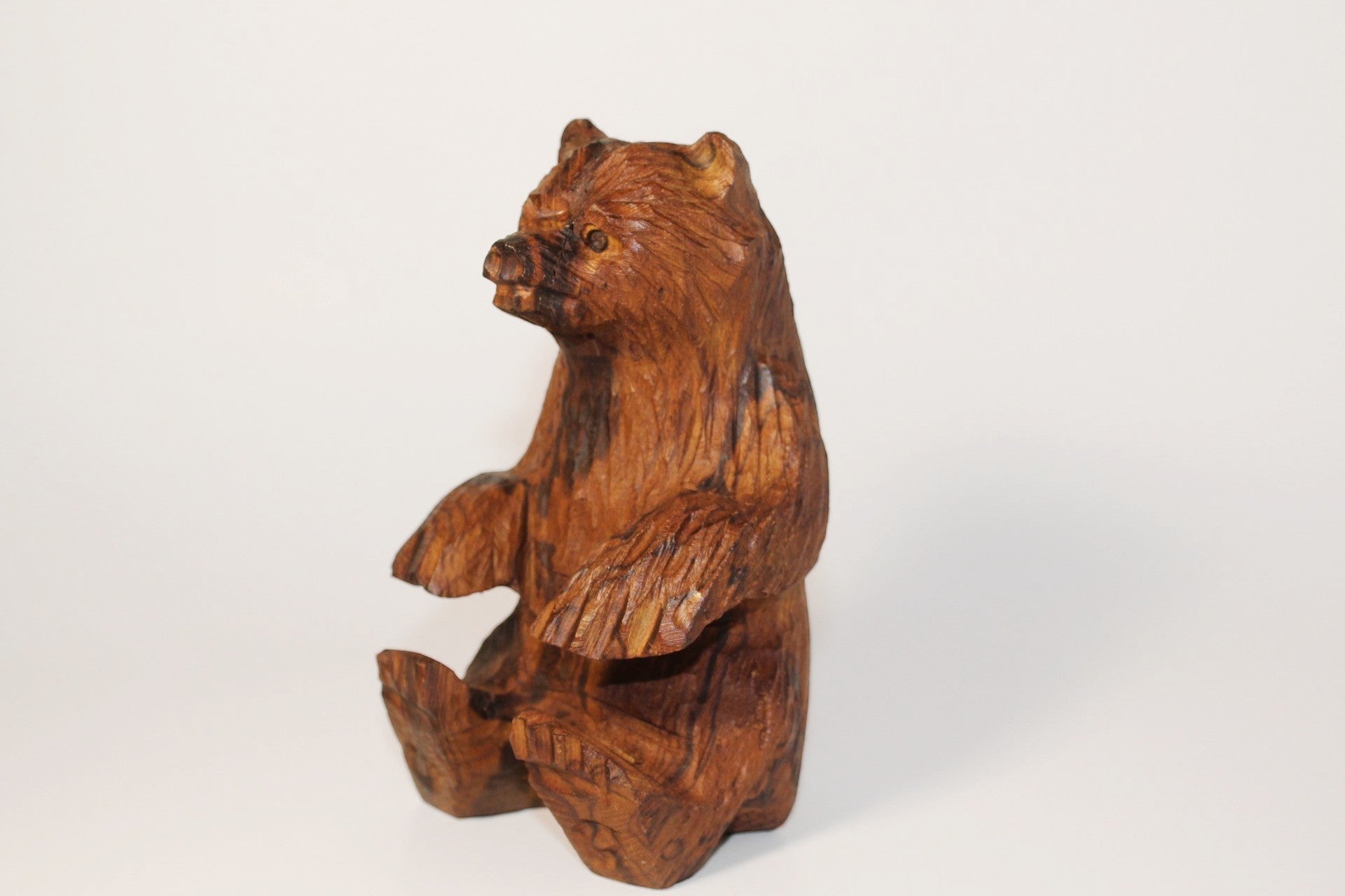 Natural Wonders USA rustic hand carved wooden bear figurine, seated position, detailed wood grain, warm earthy tones.