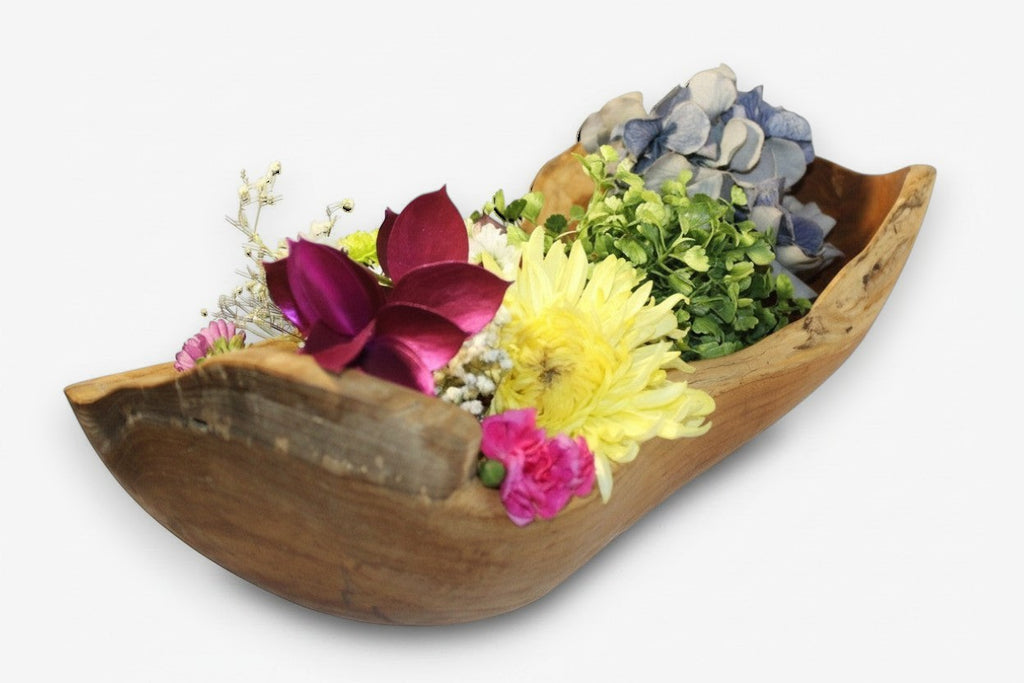 Natural Wonders USA rustic wooden trough bowl centerpiece with yellow, purple, and pink flowers and greenery.