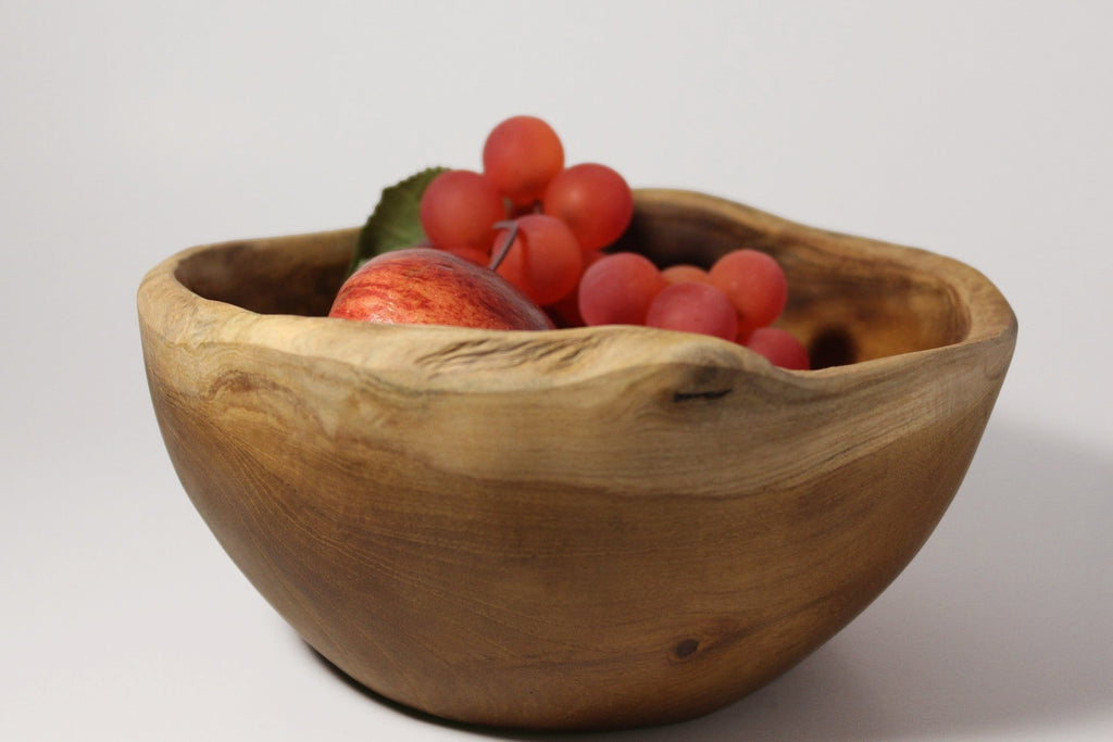 Natural Wonders USA rustic wooden serving bowl with irregular rim, filled with red grapes and an apple.