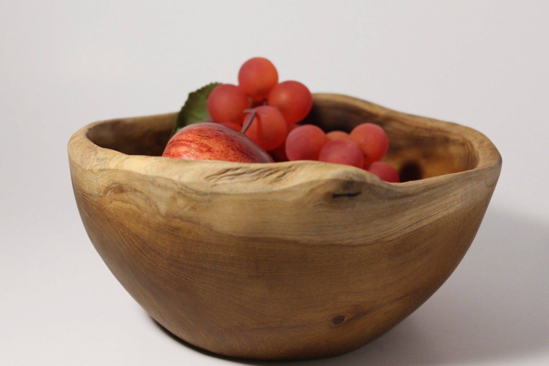 Natural Wonders USA rustic wooden serving bowl with irregular rim, filled with red grapes and an apple.